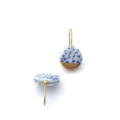 two small blue and white beads with gold ear pins on them, sitting next to each other