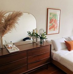 a bedroom with a bed, dresser and mirror on the wall next to each other