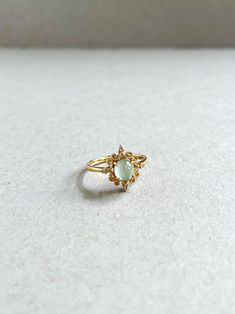 a gold ring with an opal stone in the center on a white surface,