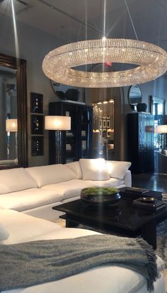 a living room filled with furniture and a chandelier hanging over the top of it