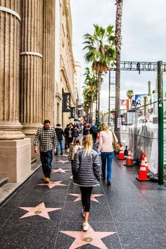 people walking on the hollywood walk of fame with pink stars in front of an old building