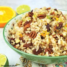 a bowl filled with rice and nuts next to sliced oranges on a table cloth