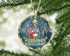 a christmas ornament with a nativity scene hanging from a pine tree branch