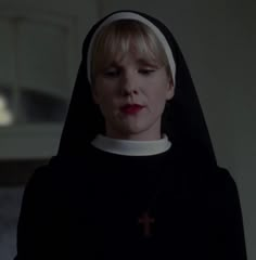 a woman with blonde hair wearing a black nun outfit