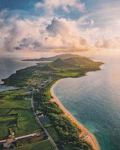 an aerial view of the ocean and coastline at sunset with clouds in the sky above