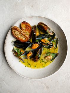 a white plate topped with mussels and bread