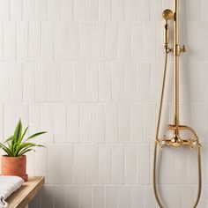 a bathroom with white tiles and a gold shower head