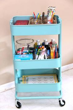 a blue cart filled with school supplies on top of a white floor next to a wall