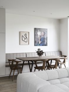 a living room filled with furniture next to a wall mounted painting on the side of a white wall