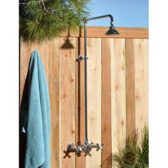 an outdoor shower with thermostaer and hand held faucet in front of a wooden fence