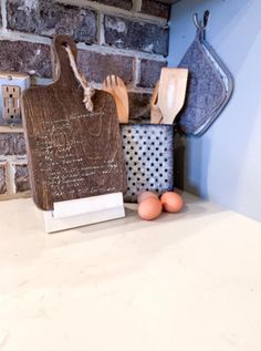 a wooden cutting board sitting on top of a counter next to eggs and utensils