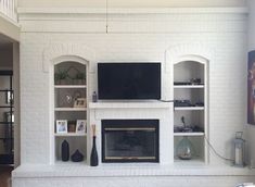 a living room with white brick fireplace and built - in bookshelves