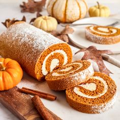 pumpkin roll on a cutting board with cinnamon sticks and other fall decorations around it,