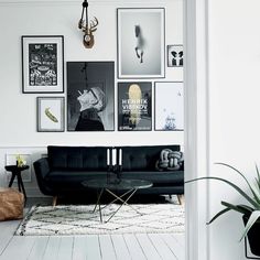 a living room with white walls and pictures on the wall above the couch is filled with black furniture