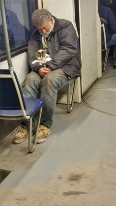 a man sitting on a train holding a cat