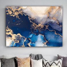 an abstract painting on the wall above a couch with pillows and throw pillows in front of it