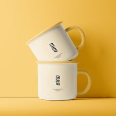 two coffee mugs stacked on top of each other in front of a yellow background