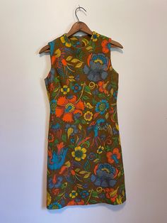 Gorgeous, fun bright vintage dress in excellent condition! Bright abstract orange, blue green and yellow print on a brown background. Back zipper closure.  Bust-35" Waist-37" Shoulder to hem-37" Vintage Printed Brown Dress, Vintage Brown Floral Print Dress, Brown Vintage Printed Dress, Vintage Brown Printed Dress, Retro Orange Printed Dress, Retro Brown Lined Dress, Retro Orange Dresses With Vibrant Print, Retro Orange Dress With Vibrant Print, Retro Brown Floral Print Dress