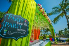 an outdoor party with neon green draping and white flowers on the table, surrounded by palm trees