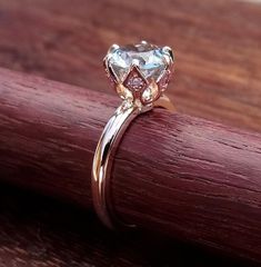 a diamond ring sitting on top of a piece of wood next to a wooden table