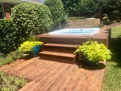 a hot tub sitting on top of a wooden deck next to a lush green yard