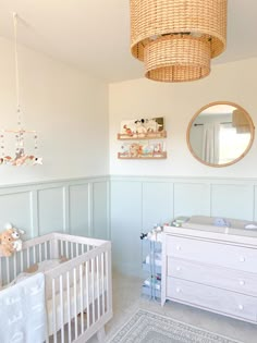 a baby's room with a crib, dresser and mirror on the wall