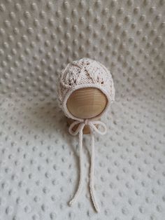 a white knitted hat on top of a crochet blanket with a wooden button