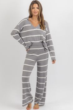 a woman in grey and white striped pajamas with her hands on her hips, posing for the