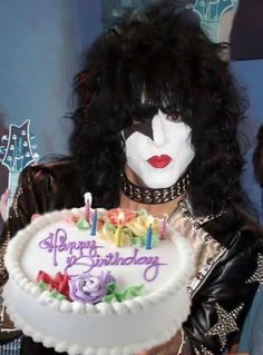 a woman with black hair and makeup holding a birthday cake