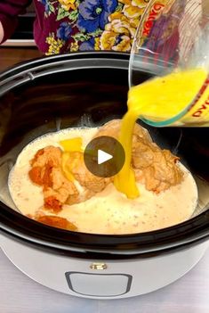 someone pouring orange juice into a crock pot filled with food