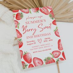 a birthday card with strawberries on it sitting next to an orange fan and palm frisbee