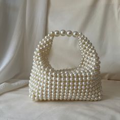 a white beaded purse sitting on top of a bed