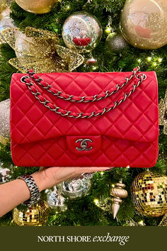 A red Chanel handbag is showcased against a backdrop of elegant holiday décor, including shimmering ornaments and a dazzling chandelier. Winter Wallpaper, Chic Handbags, Luxe Gifts