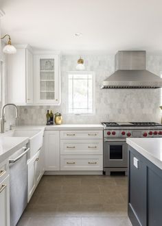 a large kitchen with white cabinets and stainless steel stove top oven in the center island