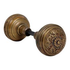 an antique brass door knob with floral design on the front and back side, isolated against a white background