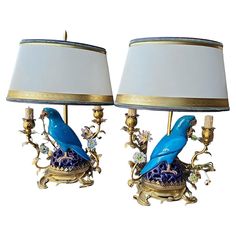 two blue birds sitting on top of lamps next to each other with gold trimmings