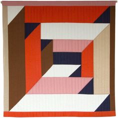 a quilted wall hanging with an orange, pink and blue design on it's side