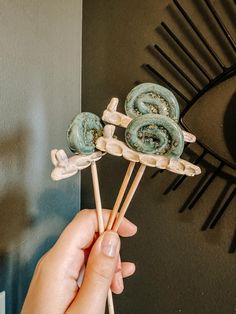 a person holding two lollipops in front of a clock