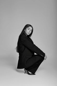 a woman is sitting on the ground in a black suit