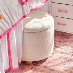 a white ottoman sitting on top of a bed next to a pink and white blanket