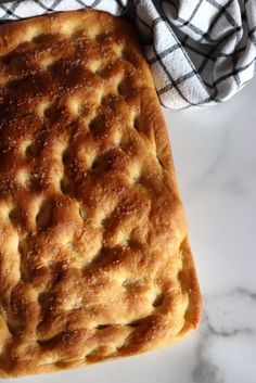 a square pastry sitting on top of a white counter next to a black and white towel