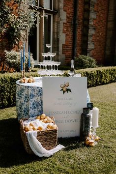 a table set up for a wedding with food and drinks on the grass in front of a building