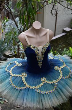 a blue and white tutu with jewels on the bottom is sitting in front of a mannequin