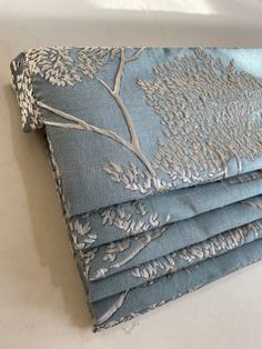 four pieces of blue and white fabric folded on top of each other with tree designs