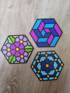 three pieces of perler bead art sitting on top of a wooden table