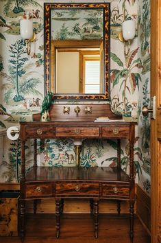 a bathroom with wallpaper and a mirror on the wall next to a wooden vanity