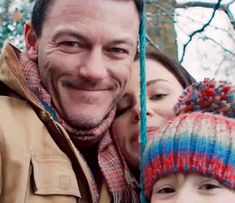 two adults and one child are smiling at the camera while wearing knitted beanies