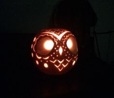 a carved pumpkin with glowing eyes and an intricate design on it's face in the dark