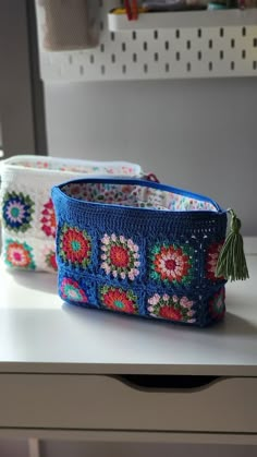 two crocheted purses sitting on top of a white counter next to each other