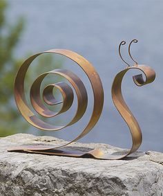 a metal sculpture sitting on top of a rock